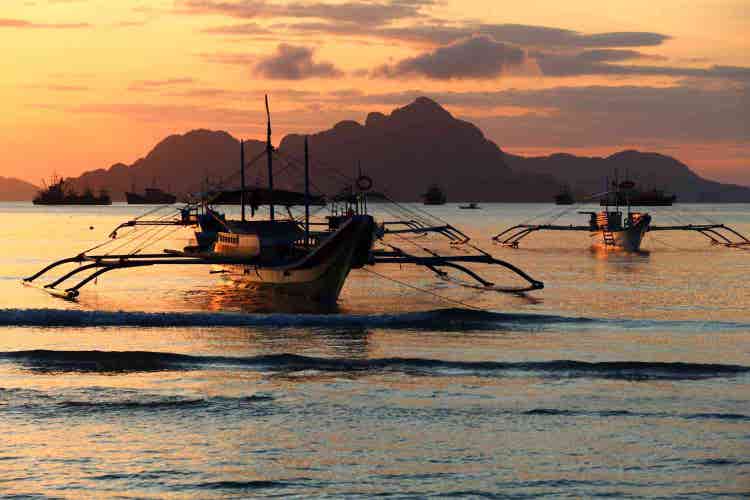 Traditional boat anchored along pristine beach with turquoise waters, golden sand, clear skies, tropical surroundings, and serene island atmosphere together.
