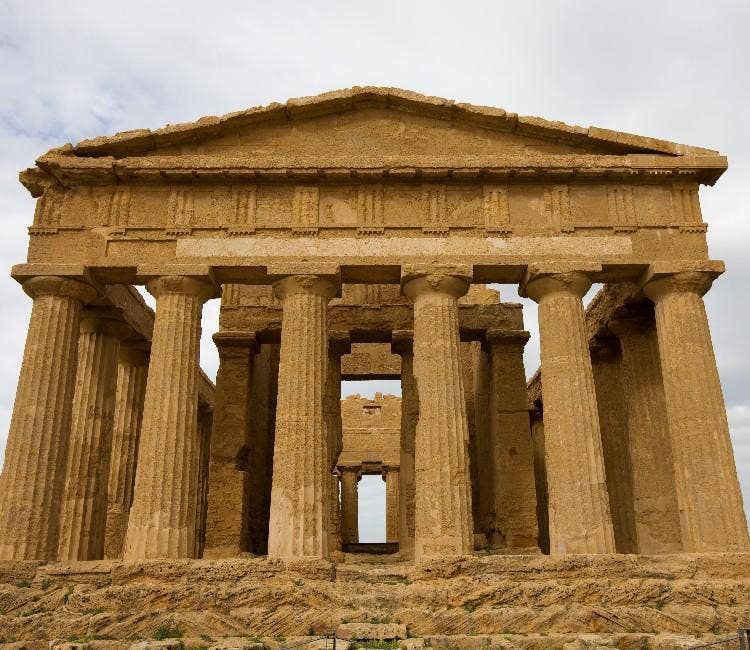 The symmetrical stone facade and fluted Doric columns of the ancient Greek Temple of Concordia in Agrigento, Sicily.