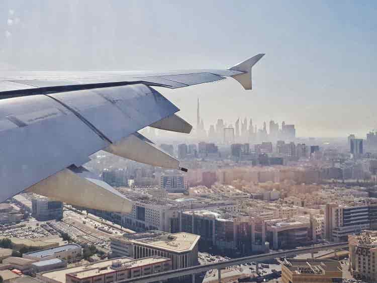 Aerial view of Dubai skyline from an airplane window showcasing towering skyscrapers, desert landscapes, modern architecture, and the city's stunning coastline.
